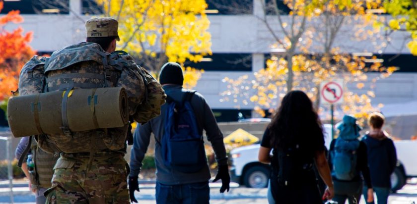 Staff and students, some in military uniform, ruck across campus