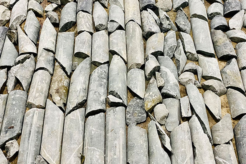 A series of grey cylindrical rocks arranged on a sandy ground.