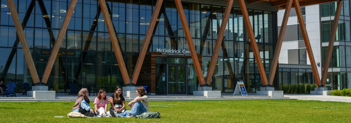 Students sitting on the lawn in front of McGoldrick.