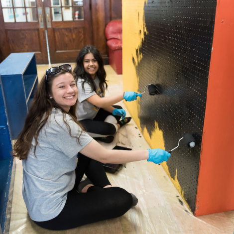 Two students painting a wall at a volunteer site.