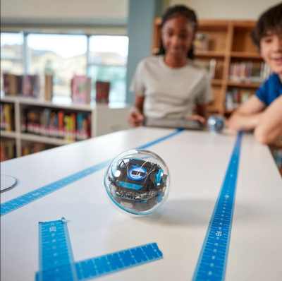 children watching a small sphere robot on the table