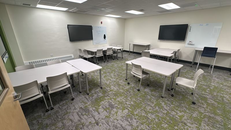 Photo of Teal classroom which has plenty of desk spaces available and 2 flat screen TV's on the wall.