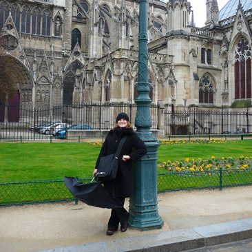 Photograph of Art History Professor, Kim Theriault, in front of gothic Cathedral
