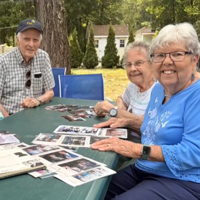 Old friends sit around table looking at photos