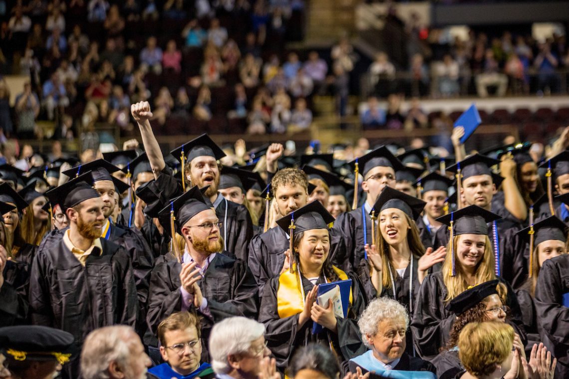 Photo of happy and excited graduates, wearing their caps and gowns during the Commencement ceremony.