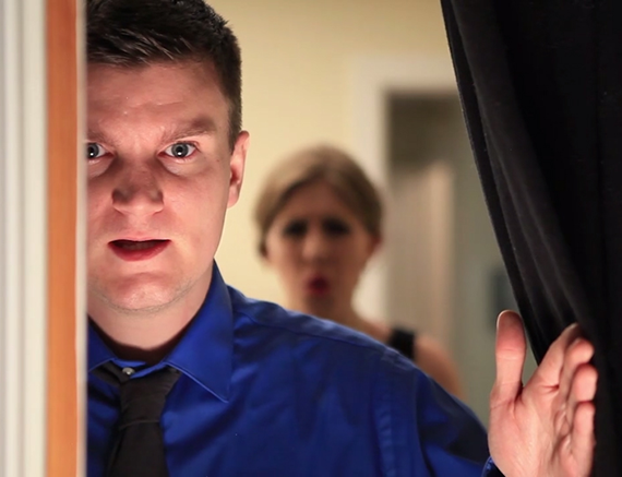 A still from student film, young man gazes from behind curtain