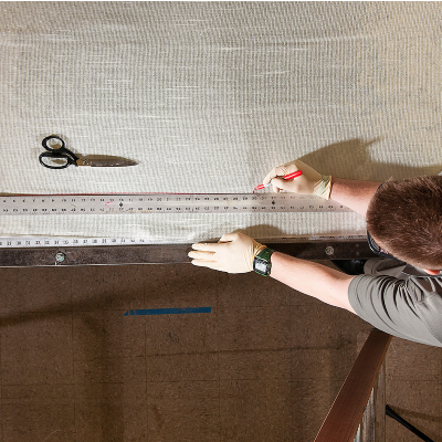 Technician measuring composite fabric along a ruler on a work surface