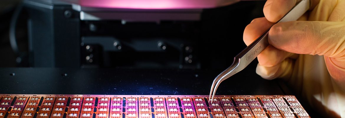 Technician handling microchips on a wafer with precision tweezers