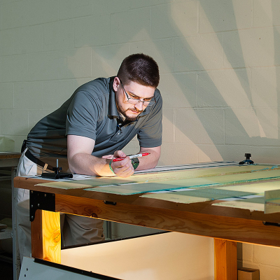 Engineer reviewing and marking a technical design at an illuminated drafting table