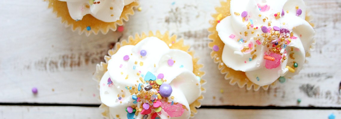 Vanilla cupcakes with sprinkles on top.