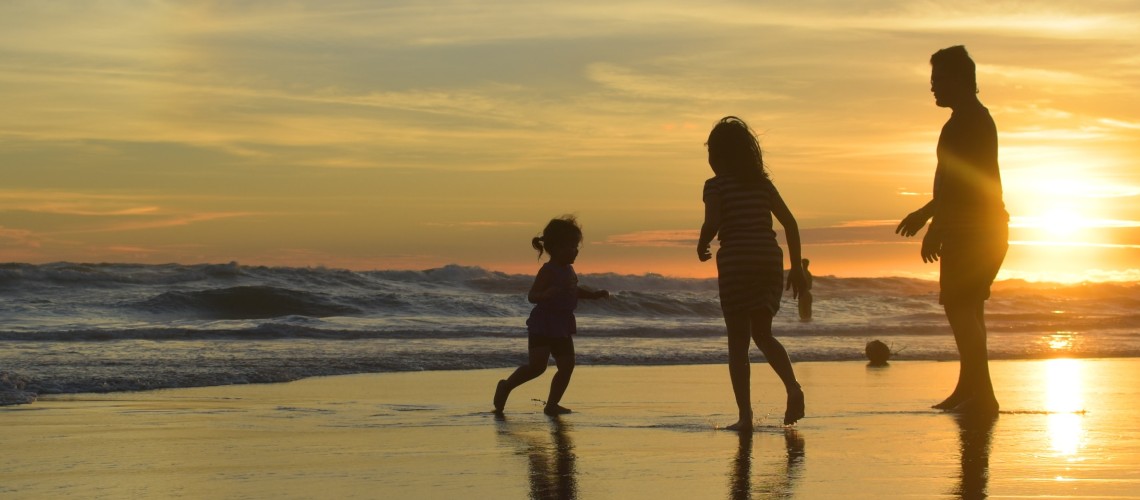 A family playing on the beach at sunset