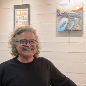 Greg Daly smiles beside his acrylic painting "Higgins" at the Employee Art Exhibition.