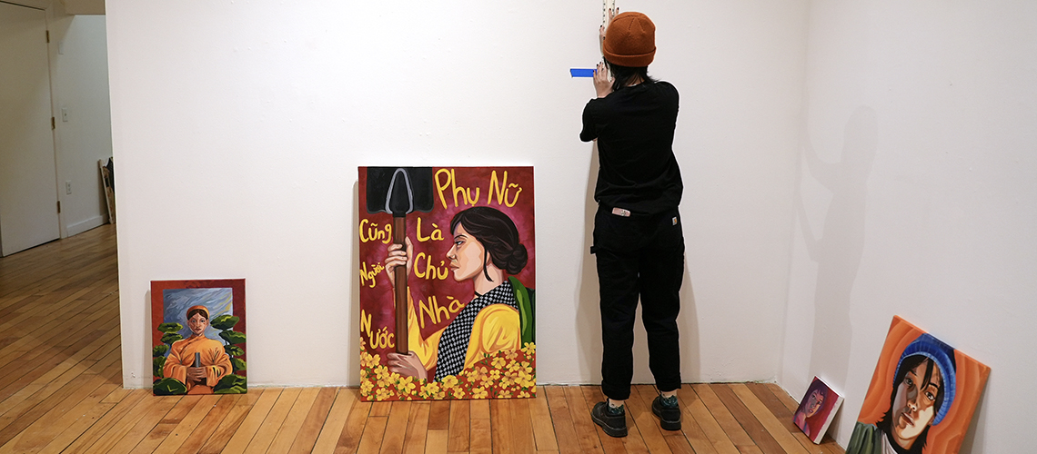 BFA student, Han Nguyen, works on hanging her work for the BFA Exhibition