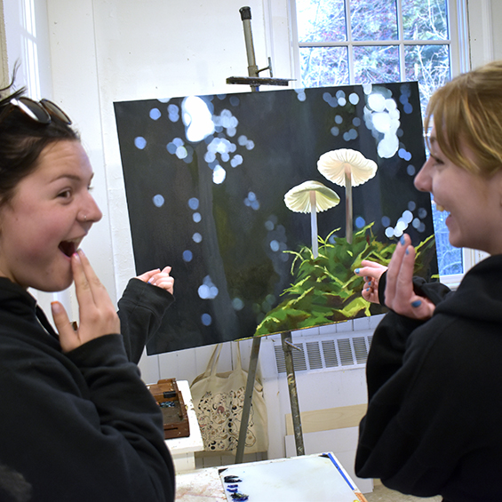 Two students exclaim excited over painting of two mushrooms in the woods.