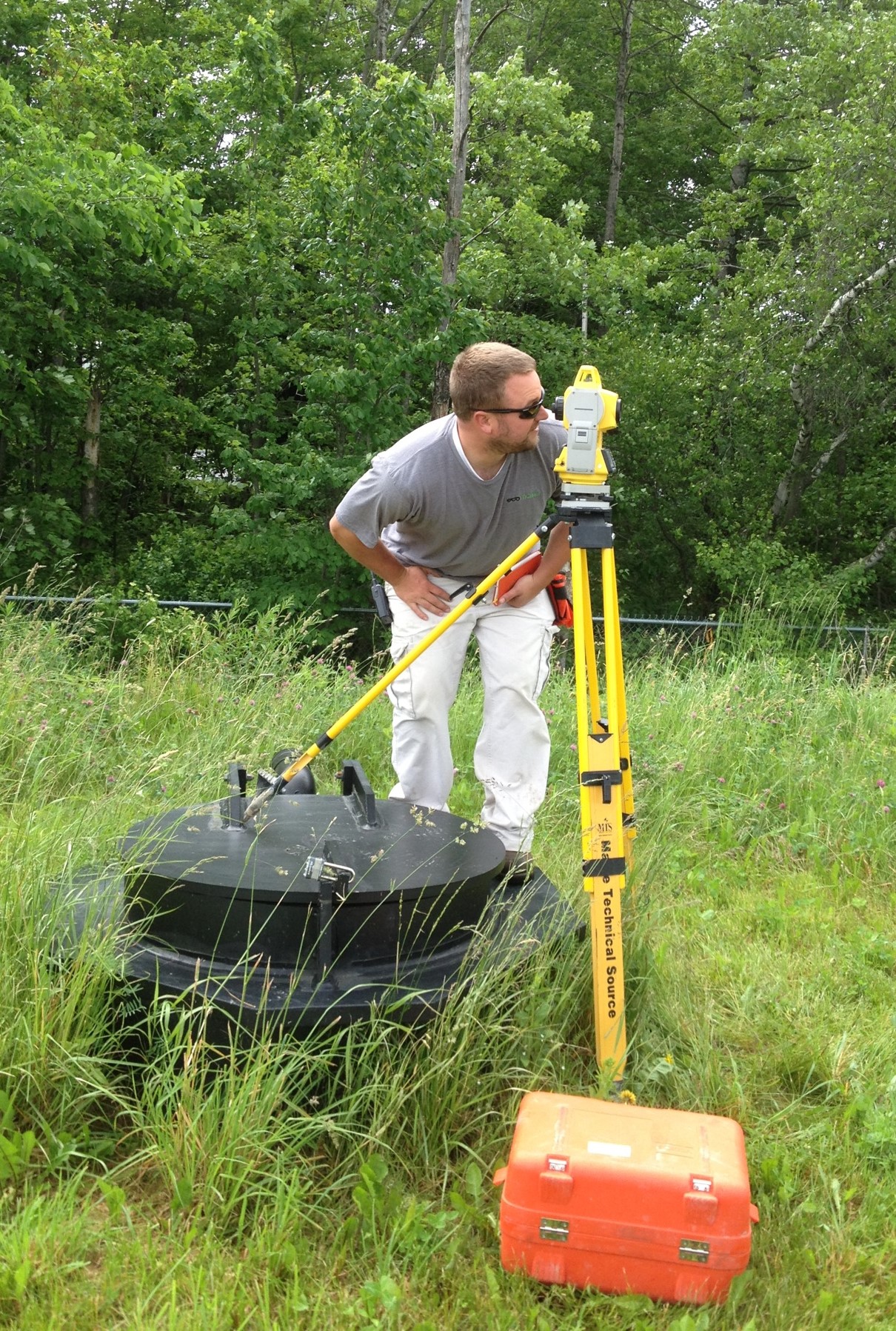 student surveying monitoring wells