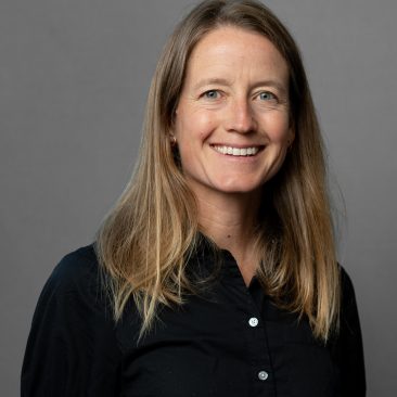 Dr. Elizabeth Parks-Stamm headshot, posed, smiling in front of dark grey background