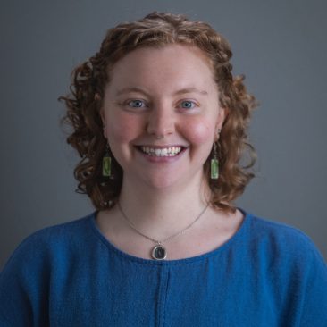 Woman smiling in a blue shirt and grey background