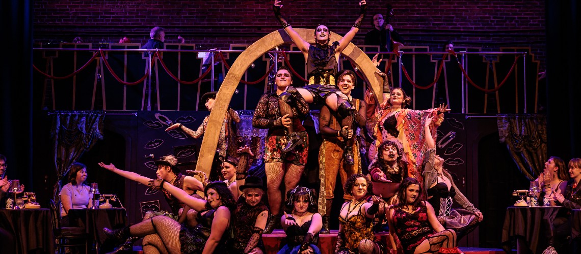 Large cast of 'Cabaret' singing on stage.