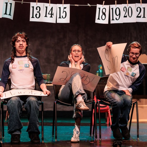Three students sit in a row. Two react to something the other said with horror.