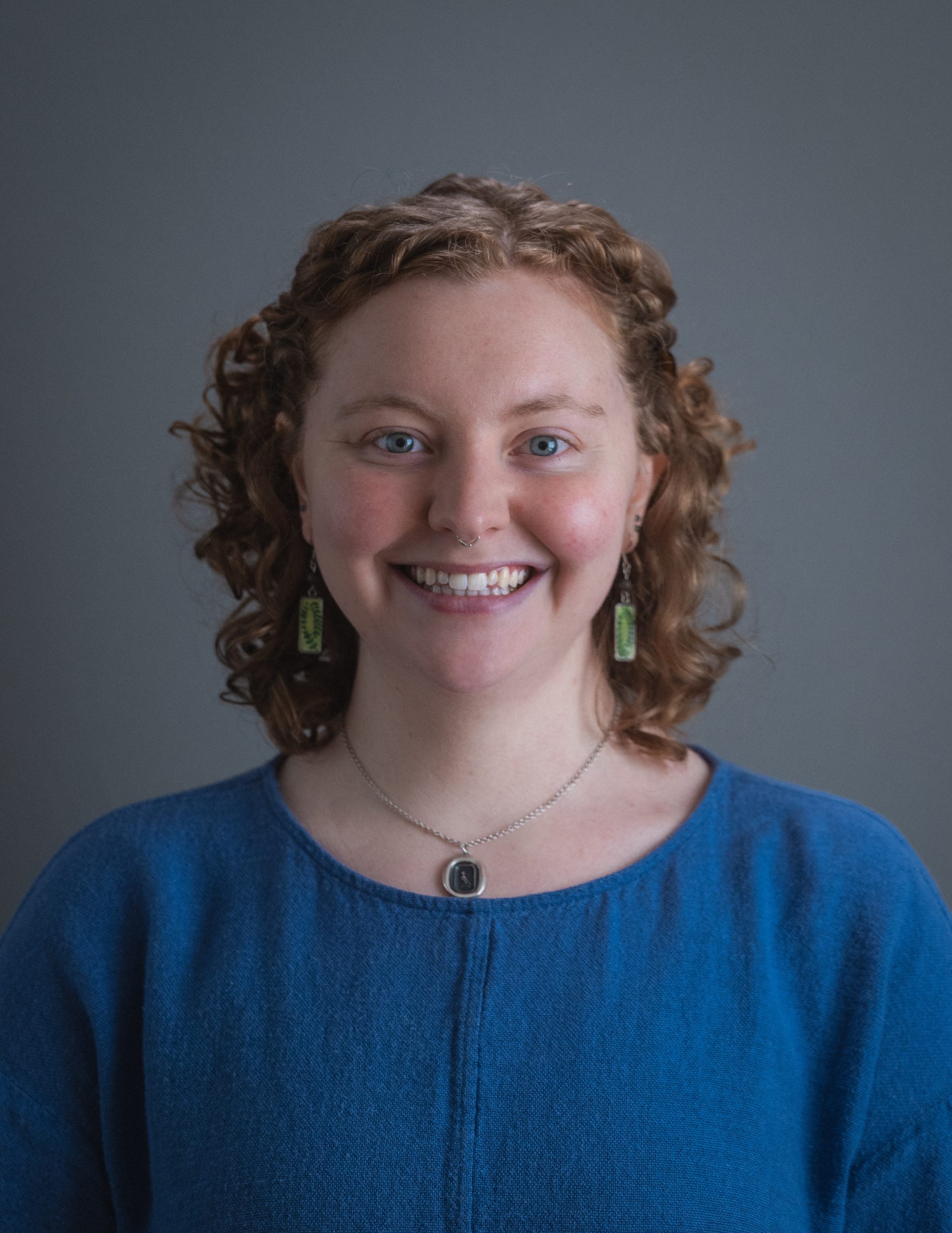 Woman smiling in a blue shirt and grey background