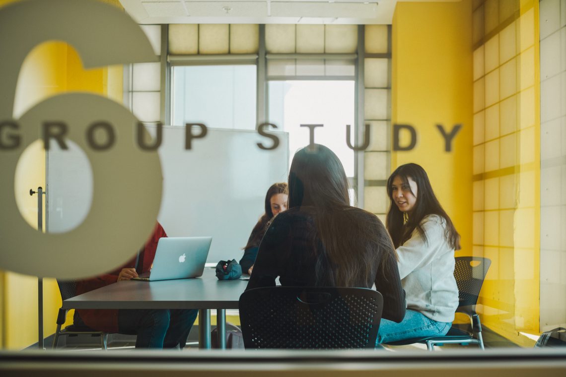 Three students sitting around a table in a USM study room