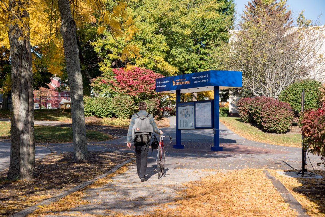 Student walks bike along path on Portland campus.