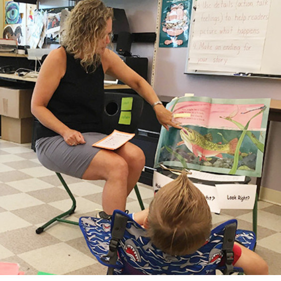 teacher with studet in a classroom reading a story