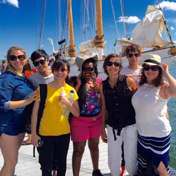Students and faculty in front of sail boat on a sunny day