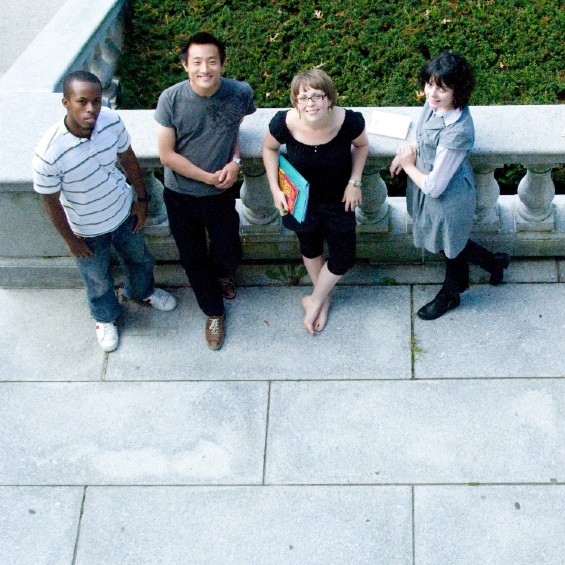 Four students lean against a railing and stare up at the camera.