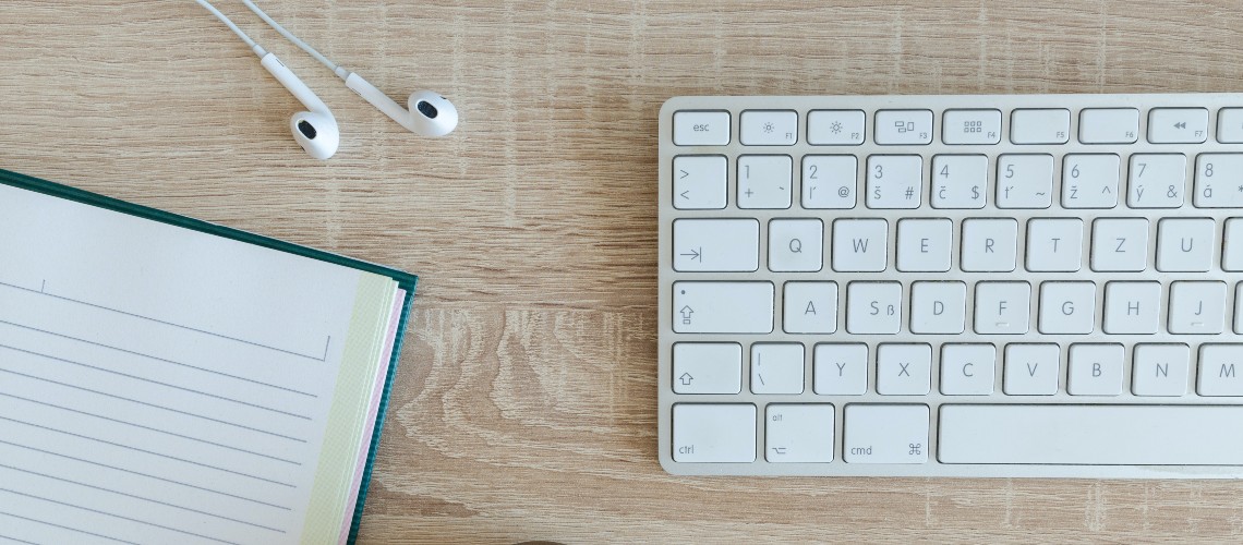 Keyboard, notebook, and headphones on a desk. Photo by Lukas Blazek on Unsplash.
  