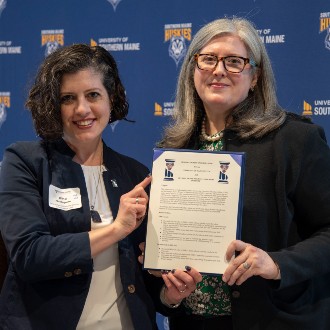 OSWLI Executive Director Christina McAnuff and Gina Guadagnino, chief of staff to the USM president, display a newly signed charter establishing USM's first alumni chapter of the Olympia Snowe Women's Leadership Institute.