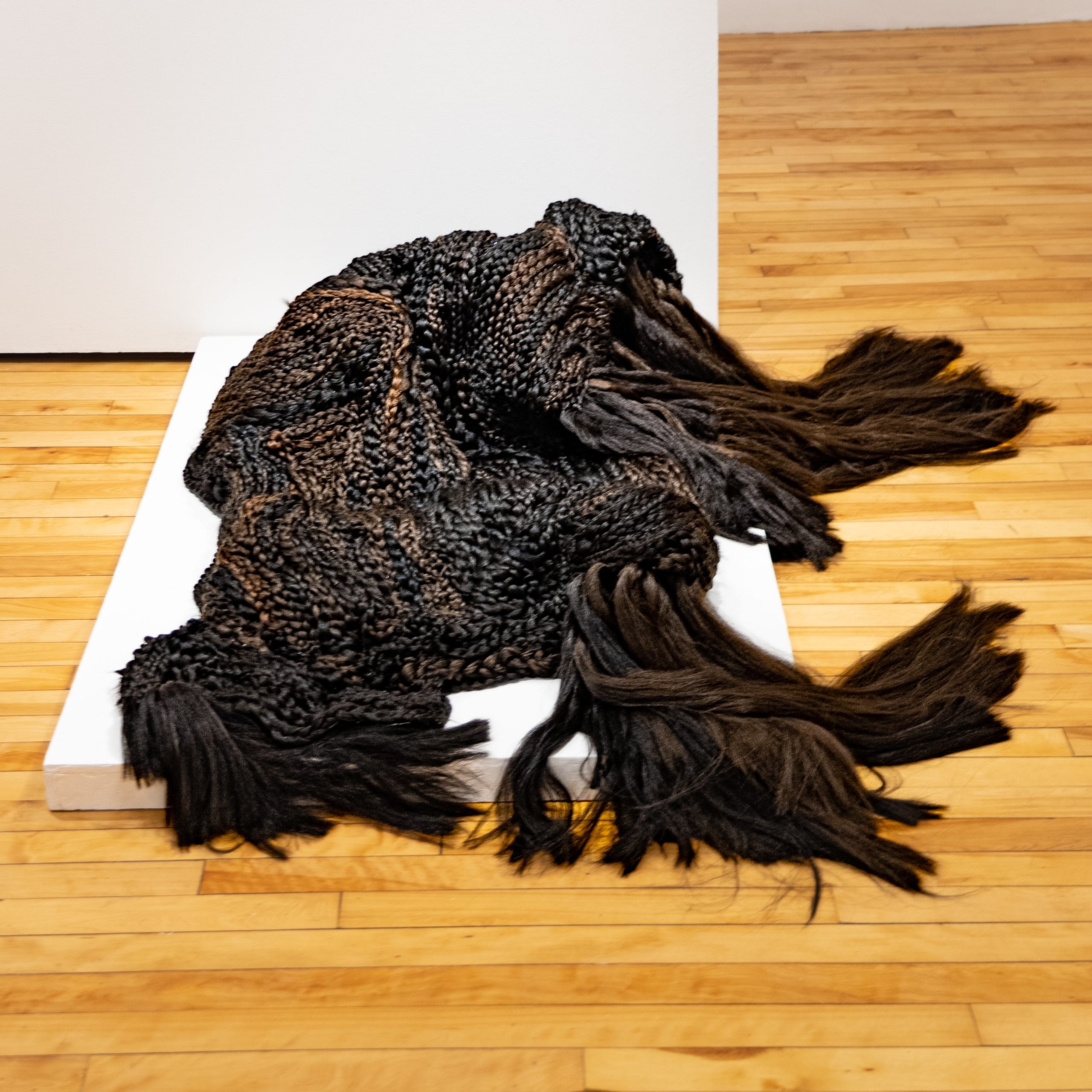 Veronica A. Perez, "you see, eventually, everything fades away," 2023. Artificial hair, bobby pins, 21 in. wide x 74 ½ in. long x 36 in. Part of shadow / echo / memory at the University of Southern Maine Art Gallery, 2023.