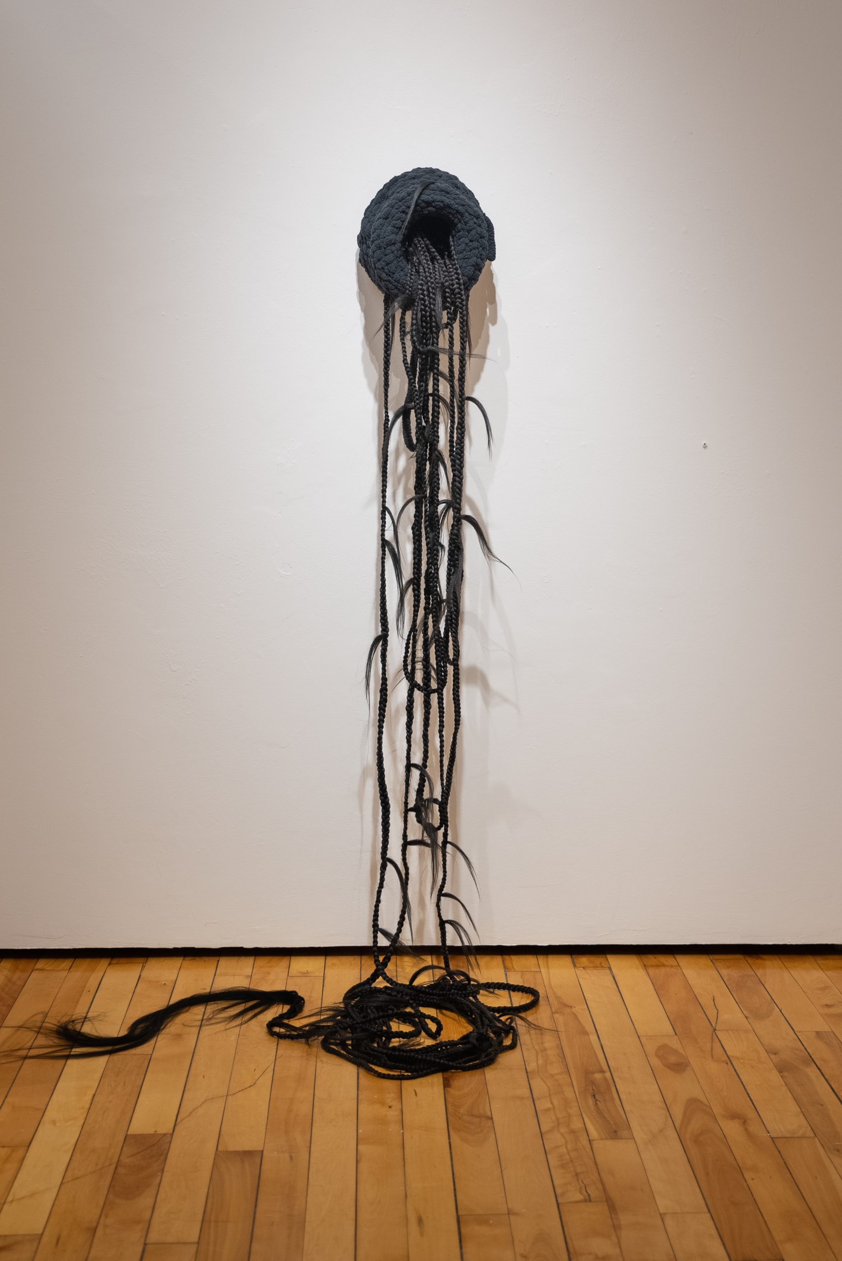 Veronica A. Perez, "infinite distance," 2023. Artificial hair, yarn, bobby pins, 72 in. tall x 12 in. wide x 9 in. deep. Part of shadow / echo / memory, University of Southern Maine Art Gallery, 2023.