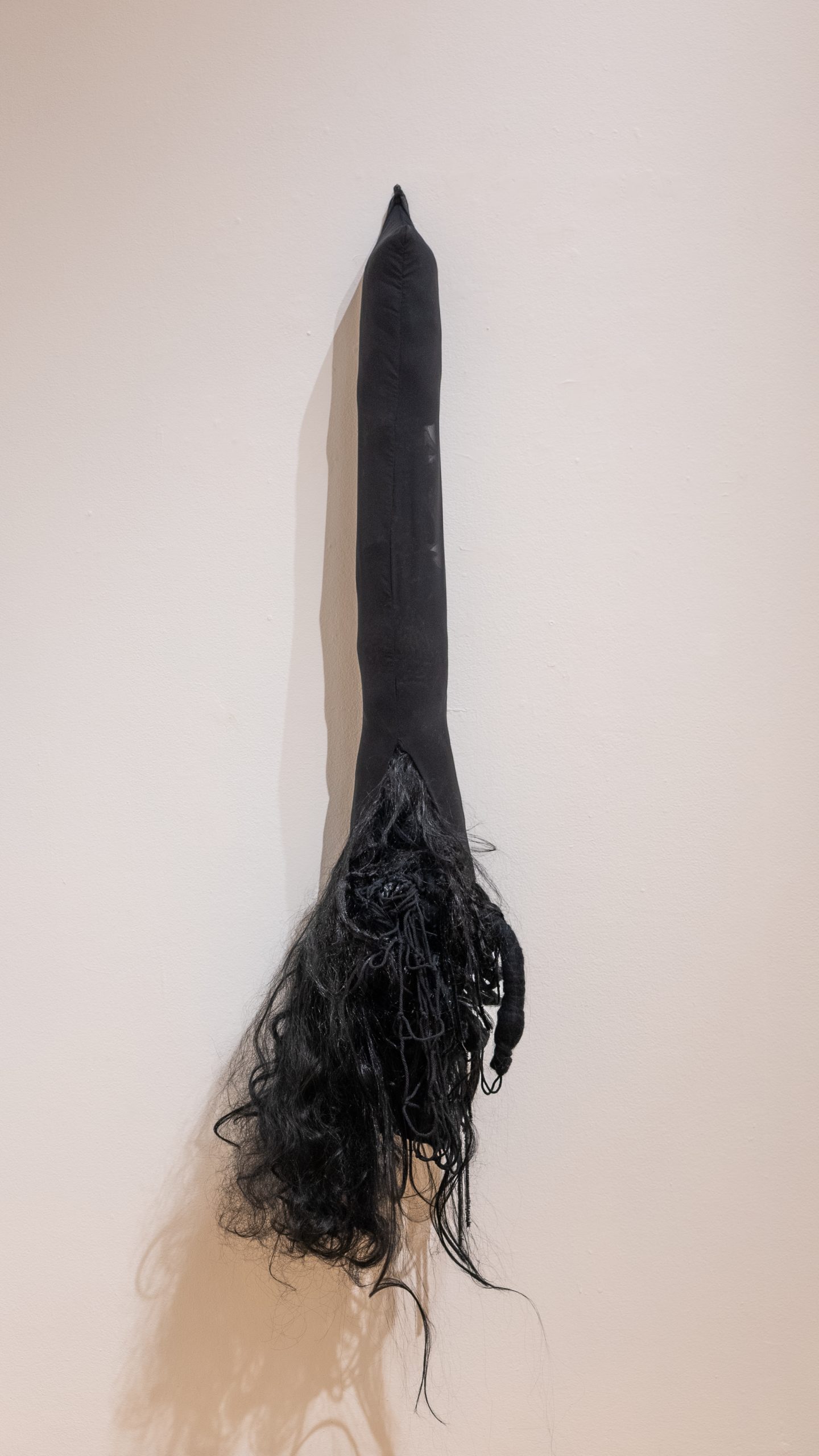 Veronica A. Perez, "splayed," 2023. Fabric, artificial hair, 66 in. tall x 16 in. wide x 11 in. deep. Part of shadow / echo / memory, University of Southern Maine Art Gallery, 2023.