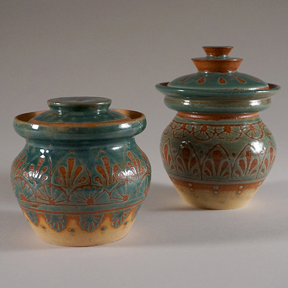 An image of two small raku-fired pots with lids.