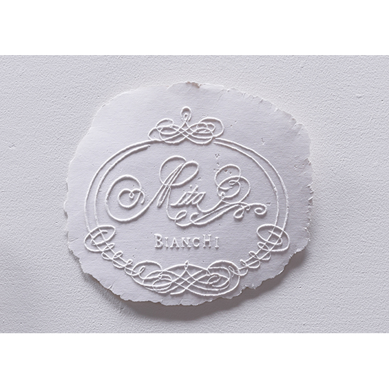 An image of a piece of paper with an intricate embossed monogram