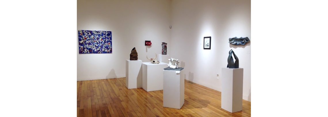 A series of artwork in a gallery. At left is an abstract painting, at right, a series of sculptures on pedestals.
