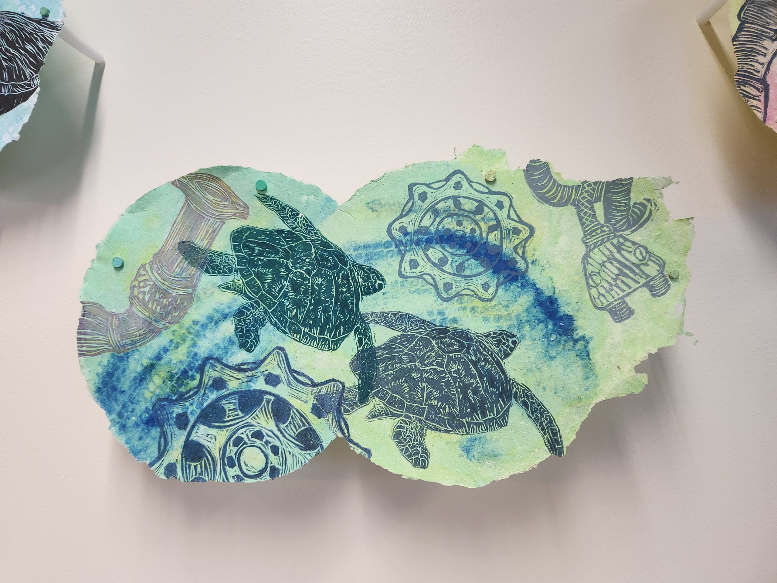 Marilyn Propp, "Travelers," 2014. Relief print on handmade cotton paper with pulp painting, 9 ¾ x 18 in. Part of "Pulped Under Pressure," 2022. Installation view, Glickman Family Library.