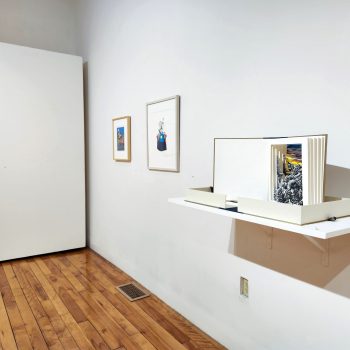 Works by Artist Annie Lee-Zimerle. Far left: works from the Perfect Wife Series, 2017-18. Far right: "View from the Window, no. 4," 2022. Tunnel book: relief print and watercolor on paper, book board, cloth and ribbon. "Hidden Stories," Installation view, 2023. University of Southern Maine Art Gallery. Photo by Kat Zagaria Buckley.