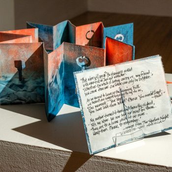 Kate Chenney Chappell, "Keys to a Home No More," 2018. Artist’s book (accordion: monotype copperleaf collage; found material; life raft nylon;) 45 in. long x 9 in. wide x10 in. high (open) / 10 x 10 in. (closed). Part of "Hidden Stories," Installation view, 2023. University of Southern Maine Art Gallery. Photo by Tricia Toms.