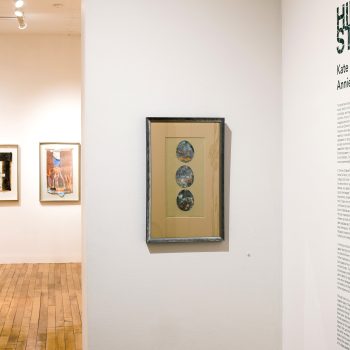 Center: Kate Chenney Chappell, "Ascendent," 2012. Mixed media (collagraph/monoprint with copper leaf), 7 x 14 in. Part of "Hidden Stories," Installation view, 2023. University of Southern Maine Art Gallery. Photo by Tricia Toms.