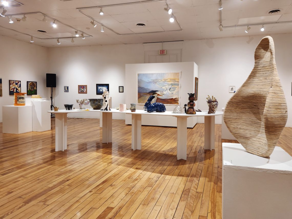 Installation view, "Parallel Convergence: The 2023 University of Southern Maine Juried Student Exhibition," University of Southern Maine Art Gallery. At right: Molly Rea, "Fixation," 2022. Plywood. 15 in. wide x 33 ½ in. tall x 16 in. deep. 2nd Place Winner, Best-in-Show.