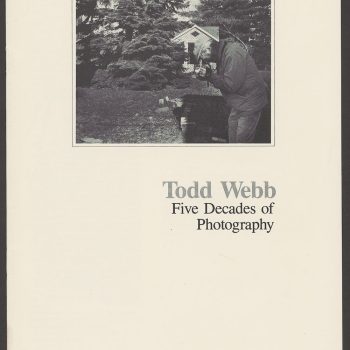 An image of a catalog cover featuring a photograph of a man in a backyard peering in a camera on a tripod