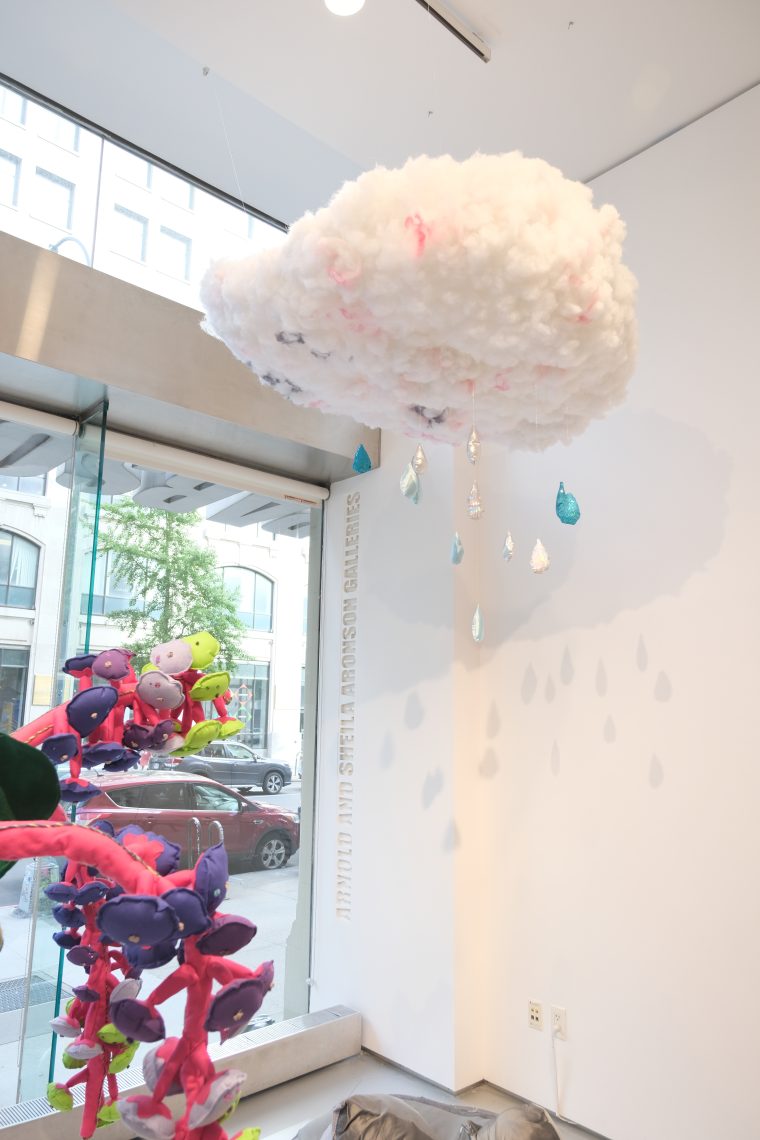 An image of a cotton cloud hanging in a gallery and raining blue and clear gems in raindrop shapes down