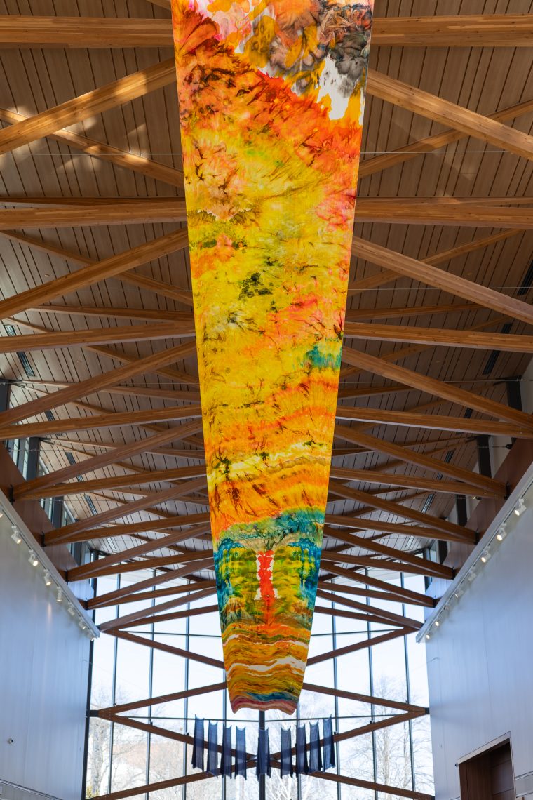 Foreground: Samantha Jones, "Whale Belly, Whale Mountain," 2026. Hand painted silk velvet, aluminum pipe, cable; 54 in. wide by 90 ft. long.  Background: Susan Bickford, "Invoking the Muses," 2026. Nine handmade blue cotton voile dresses, cotton line. Dimensions variable. Part of "Of Sibyls and Source: Ranges and Ruptures," 2026. Crewe Center for the Arts at the University of Southern Maine. Photo: Marion Earley.
