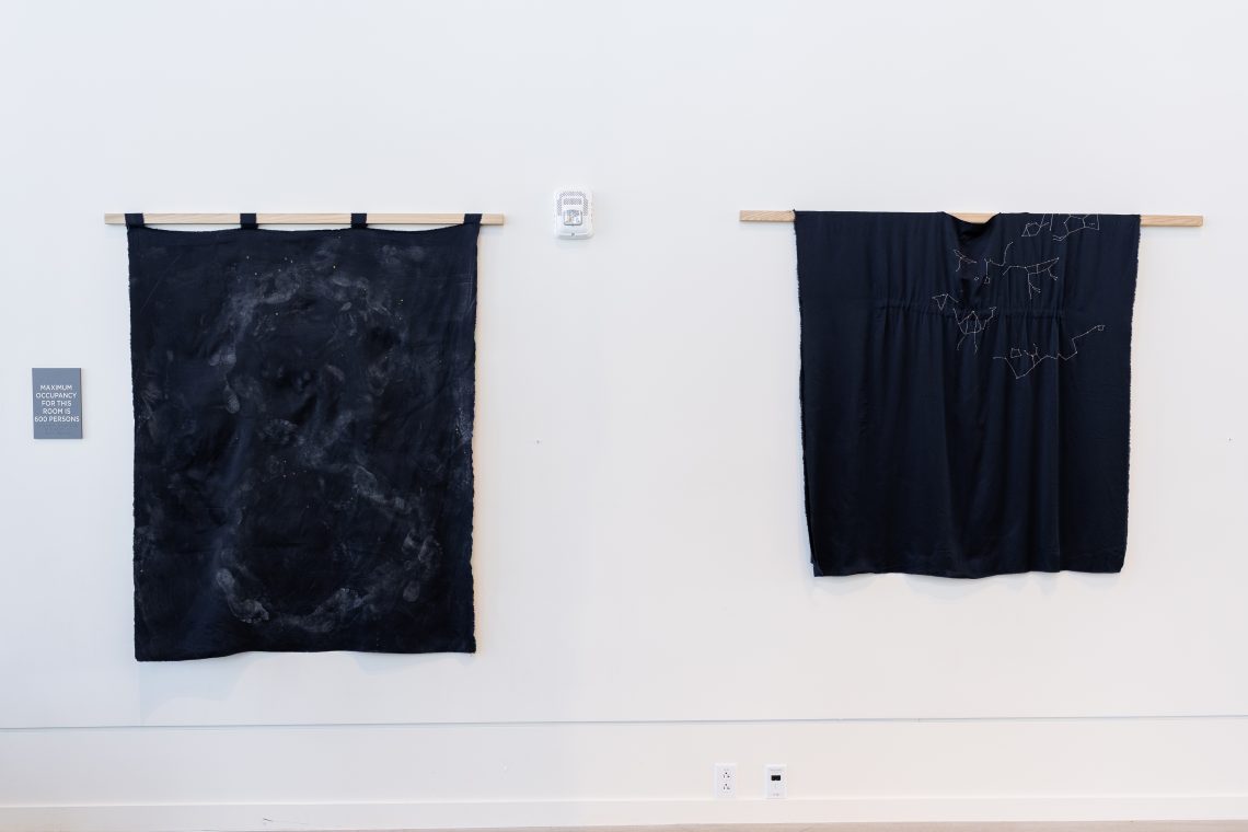 Work by artist Susan Bickford. Left: "Honeybee Heart, I am the Bridge, "2024. Silk, chalk, “dragons blood”, bee pollen, rabbit skin glue, honeybee heart Qigong. 3 ft. wide x 7 in. thick x 4 ft. high. Right: "Nut’s Garment: What do we Carry?," 2024–25. Silk, hand embroidery, silver thread. 3 ft. 9 in. wide x 3 ft. 9 in. long. Part of "Of Sibyls and Source: Ranges and Ruptures," 2026. Crewe Center for the Arts at the University of Southern Maine. Photo: Marion Earley.