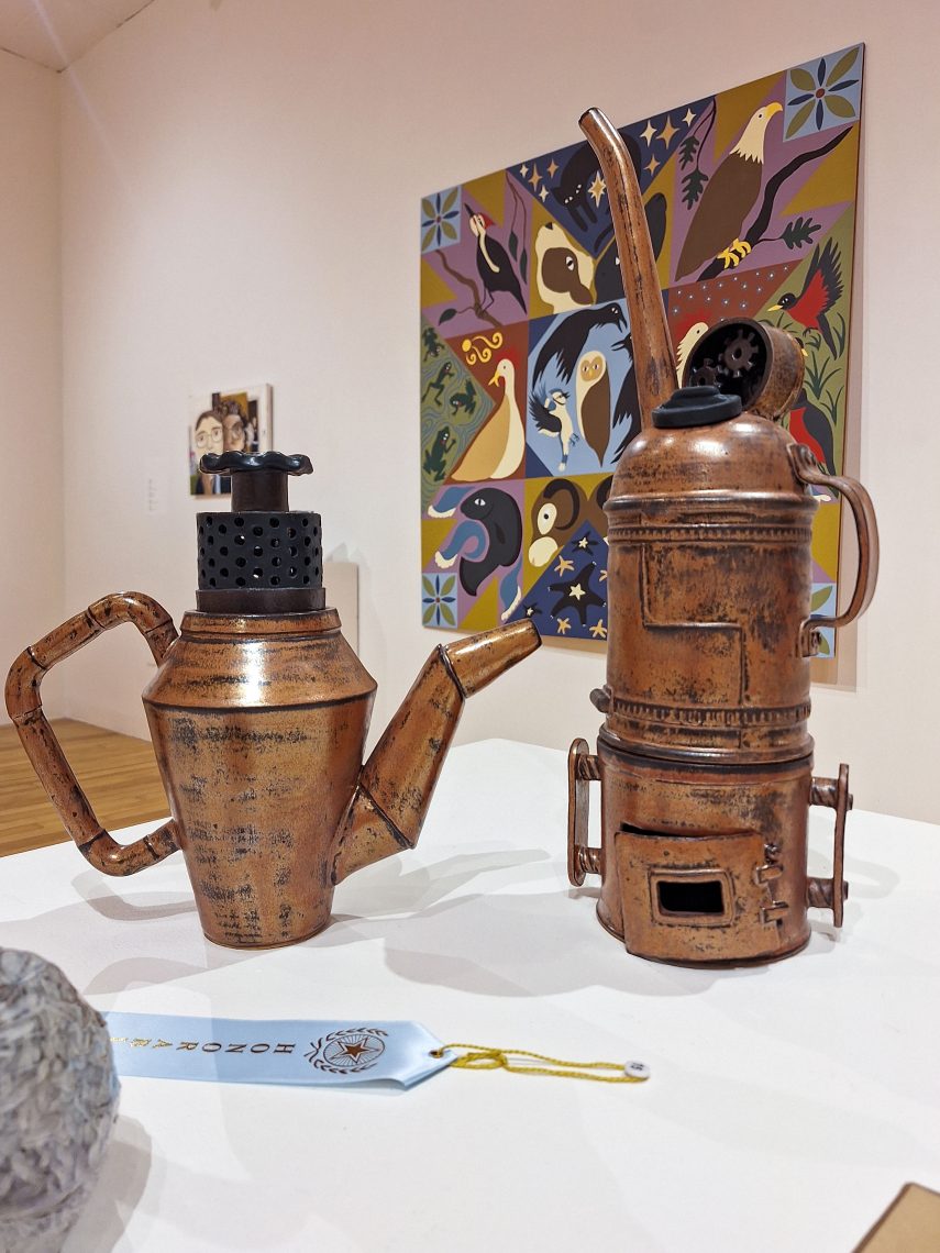 Two copper vessels, one on the right resembling a kettle, and one on the left resembling a gas canister.