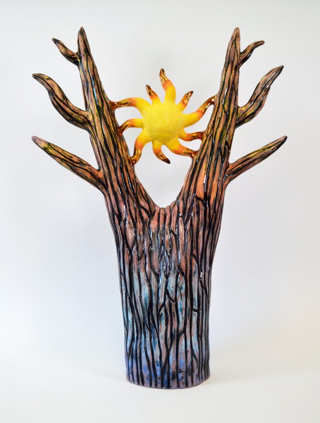 In image of a ceramic which is a stylized tree with a sun held in its branches