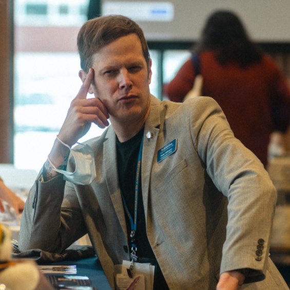 a student sits, with their pointer finger to their temple, looking deep in thought.