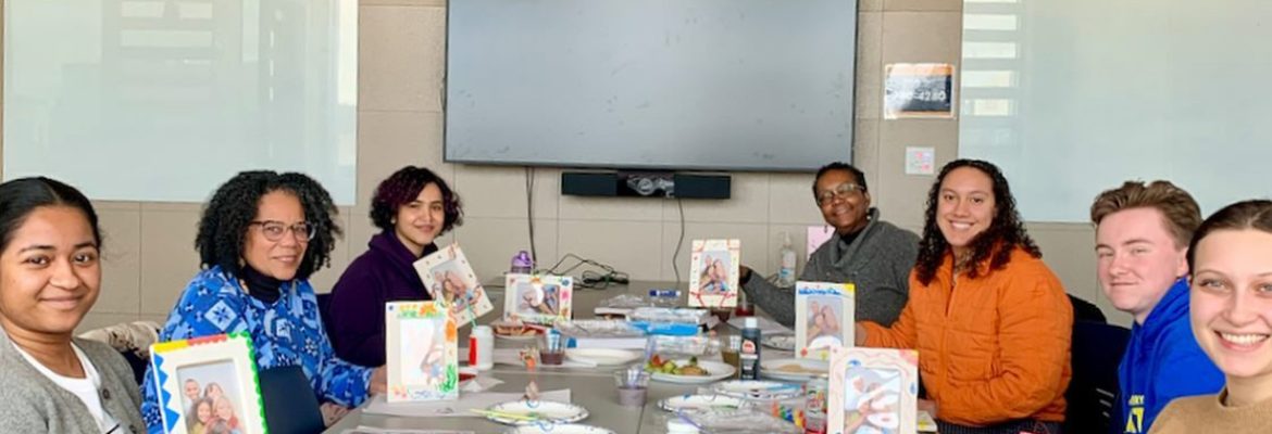 Scholars of Color mentors and mentees holding up painted picture frames as part of a workshop activity.